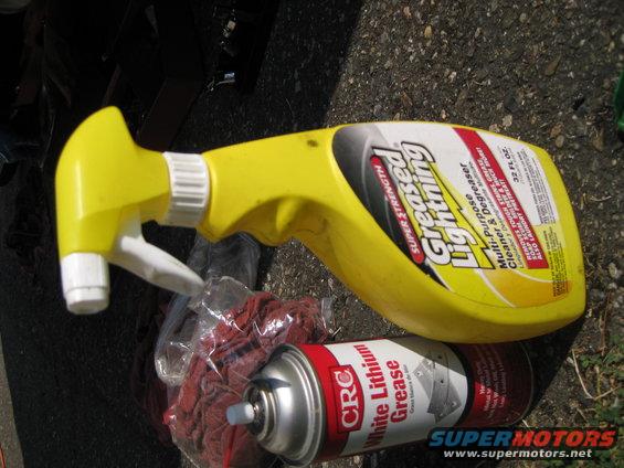 Yellow spray bottle and can of white lithium grease on asphalt
