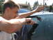 2003 Ford Crown Victoria - Person cleaning a car window with a squeegee, revealing markings on the glass.