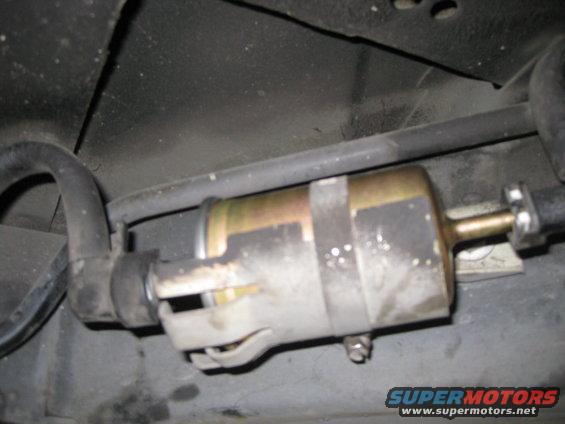 Close-up of a fuel filter with hoses attached, mounted under a vehicle