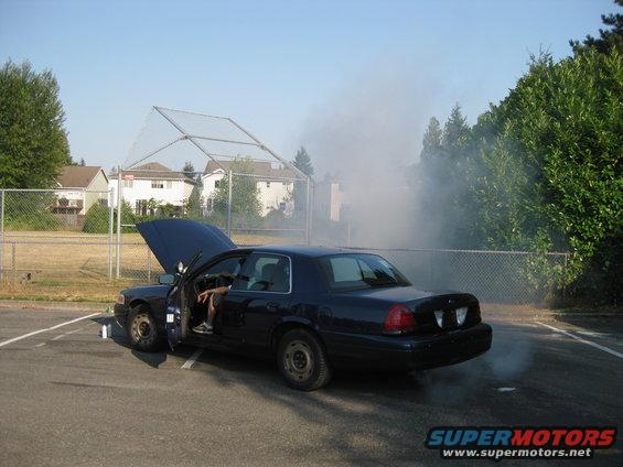 2003 Ford Crown Victoria with hood open, smoke billowing from engine compartment