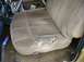 1986 Ford Bronco - The interior of a vehicle shows a worn-out tan seat with visible damage and a spray can on the floor.