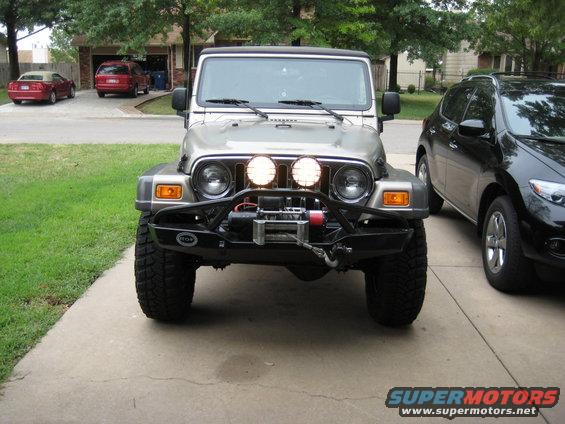 Silver Jeep Wrangler front view with aftermarket bumper, winch, and PIAA lights