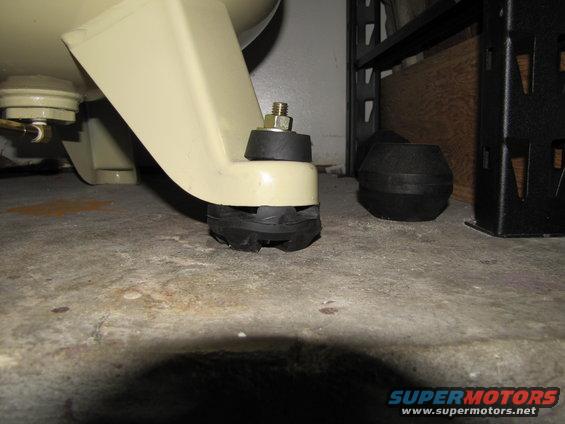 Close-up of rubber and metal mounting feet for an air compressor on a concrete floor