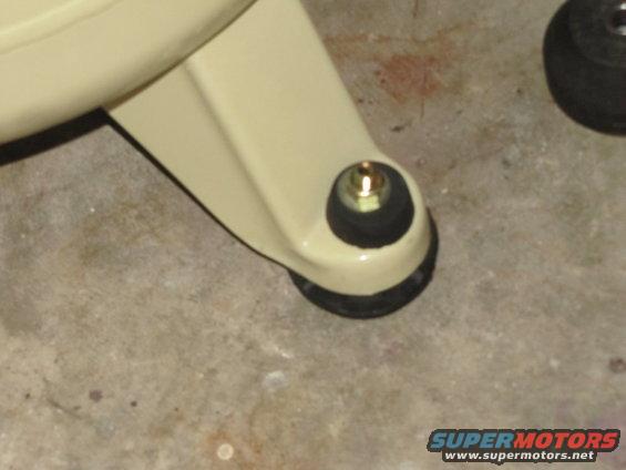 Cream-colored suspension part with a rubber bushing and bolt on a concrete floor