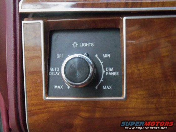 Dashboard interior with wood trim and a rotary knob for light control labeled 'LIGHTS', 'OFF', 'AUTO DELAY', 'MAX', 'MIN', 'DIM RANGE'