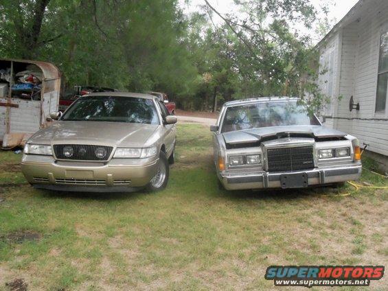 Gold sedan and a silver sedan parked on grass, one has its hood up
