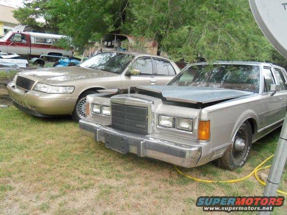 Gold sedan and silver sedan parked outside, hood of silver sedan is open