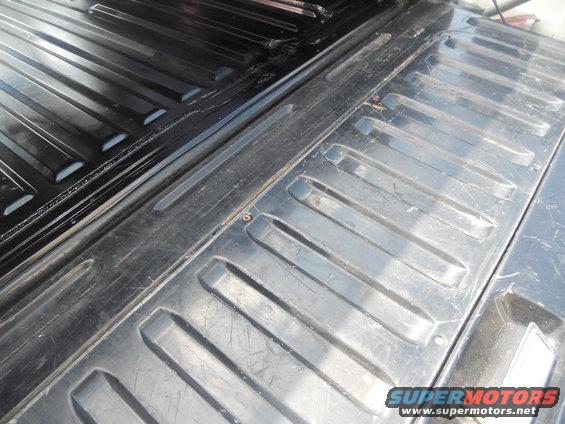 Black ribbed truck bed liner with visible wear and tear