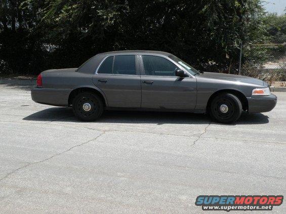 Gray 2003 Ford Crown Victoria sedan, side view, parked on cracked asphalt