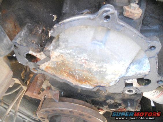 Damaged metal engine component with rust and white residue, viewed from below