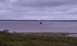1979 Ford Bronco - A small boat travels across a calm bay under an overcast sky.