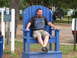 1979 Ford Bronco - A man relaxes in an oversized blue chair, with a dark SUV visible behind him.