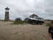 1979 Ford Bronco - Ford Bronco and two trucks parked on a sandy beach near a lighthouse and a house.