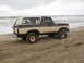 1979 Ford Bronco - Two-tone 1979 Ford Bronco parked on a sandy beach with the ocean in the background.
