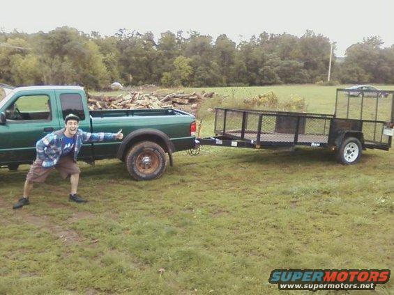guy giving thumbs up next to green pickup truck towing a trailer