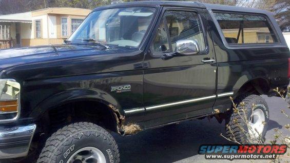 Black 1995 Ford Bronco with rust and large tires, 3/4 front view