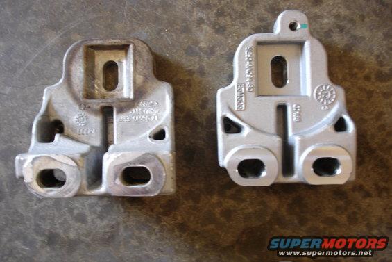 Two metal mounting brackets, one with visible Ford branding, on a textured surface
