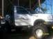 1989 Ford Bronco - A white pickup truck with custom graphics and oversized tires is shown, partially obscured by another vehicle. The photo is dated 02/01/200…