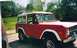 1974 Ford Bronco - A red and white Ford Bronco is parked in a driveway on a sunny day with trees in the background.