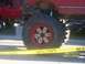 1989 Ford Bronco - A lifted red Ford Bronco with custom wheels and large tires is parked next to another red truck.