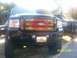 1989 Ford Bronco - A black Ford F-Series truck with a custom flame grille is parked next to another truck.
