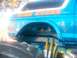 1989 Ford Bronco - A blue monster truck with custom graphics is shown from the side, large tires and suspension components.