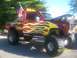 1989 Ford Bronco - Customized red pickup truck with flame graphics and an American flag displayed at an event.