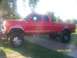 1989 Ford Bronco - This lifted red pickup truck is shown from the side.