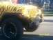 1989 Ford Bronco - This Jeep Wrangler is customized with a yellow and black tiger stripe paint job and large off-road tires.