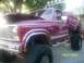 1989 Ford Bronco - This lifted pickup truck has custom paint and large off-road tires. The hood is open, revealing the engine bay.