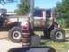 1989 Ford Bronco - A heavily modified truck with oversized tires and a roll cage is displayed outdoors.