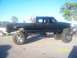 1989 Ford Bronco - A heavily modified black pickup truck with oversized tires is parked outdoors on a sunny day.