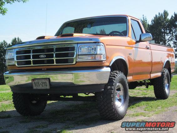 Orange 1995 Ford F-150 pickup truck with chrome grille and bumper, lifted suspension, and aftermarket hood scoop