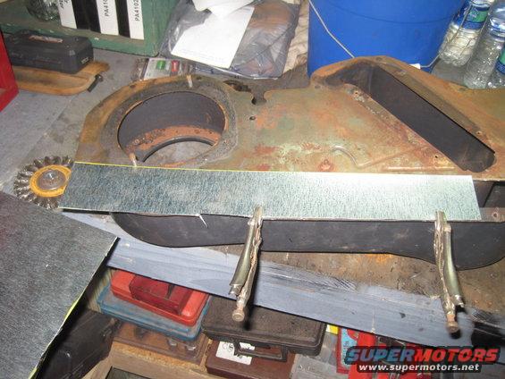 Rusted metal component clamped to a workbench with sheet metal overlay
