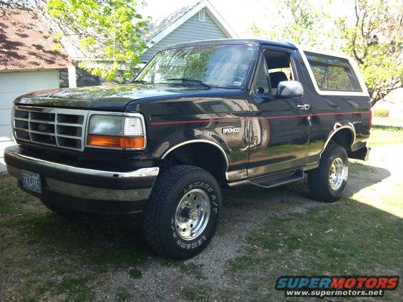 Black Ford Bronco parked in a driveway. It has a red stripe along the side and chrome trim
