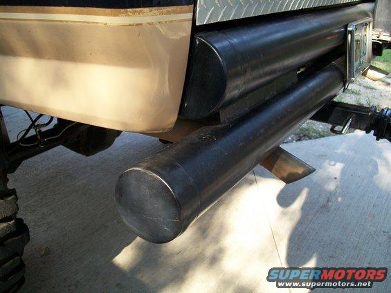 Rear bumper with dual exhaust pipes and a tow hitch. Diamond plate is visible above the bumper