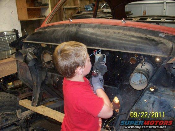 Child in red shirt works on car's engine bay, 09/22/2011
