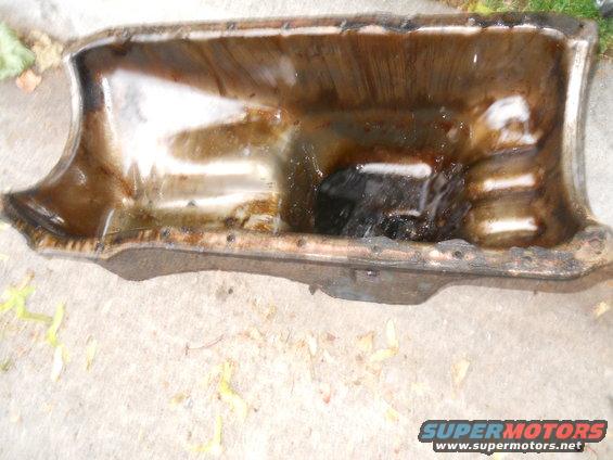 Dirty oil pan with some liquid inside, sitting on concrete