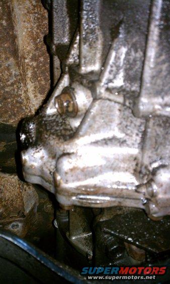 Close-up of a greasy, possibly leaking transmission housing with a bolt visible