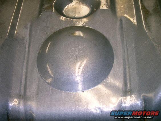 Underside of a metal fuel tank with circular indentations and raised ridges