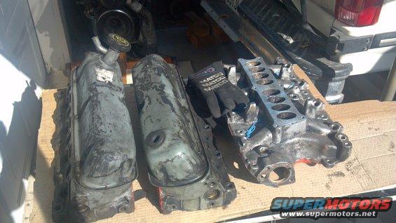 Engine valve covers and intake manifold laid out on wooden planks