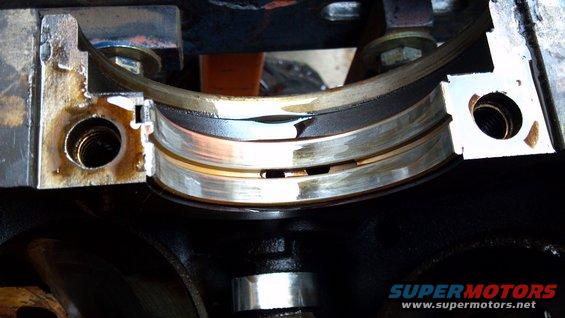 Engine crankshaft bearing with visible wear and oil