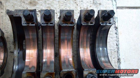 Engine crankshaft bearings with visible wear marks and some copper showing through