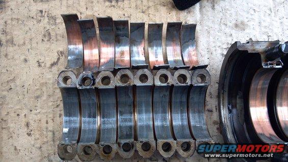 Engine bearings with copper wear, laid out on a concrete surface