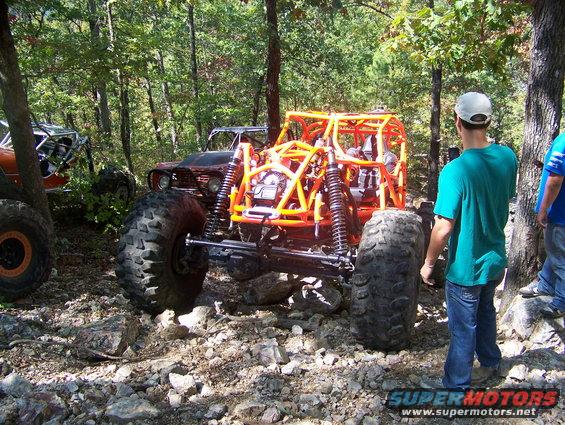 Off-road buggy with orange roll cage and large tires on rocky terrain