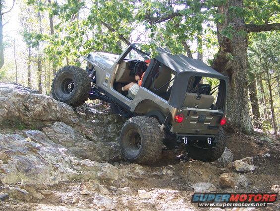 Gray Jeep Wrangler climbing rocks, large tires, soft top