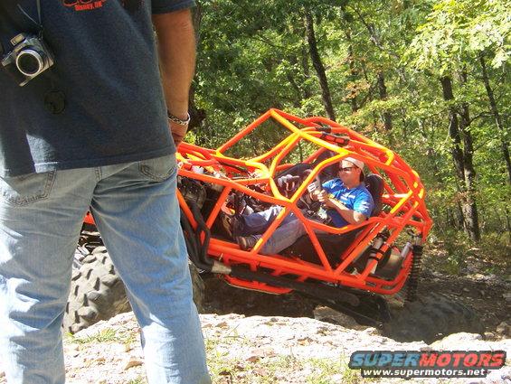 Orange off-road buggy with driver on rocky terrain