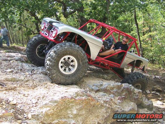 Silver off-road buggy with red roll cage on rocky terrain