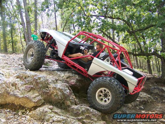 Off-road buggy with red roll cage and silver body on rocky terrain