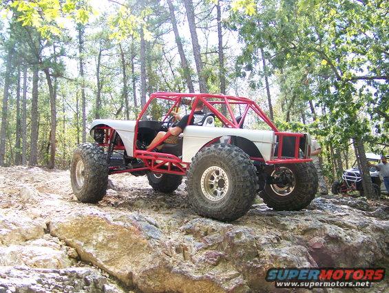 Custom off-road buggy with red roll cage on rocky terrain, another buggy visible in background